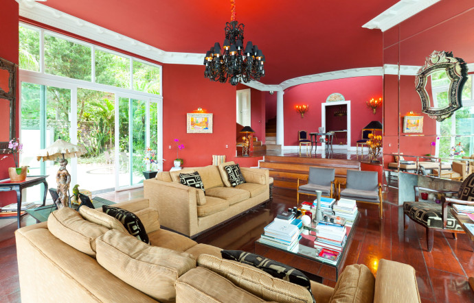 Le salon, dans lequel le rouge domine, s’ouvre sur un jardin luxuriant.
