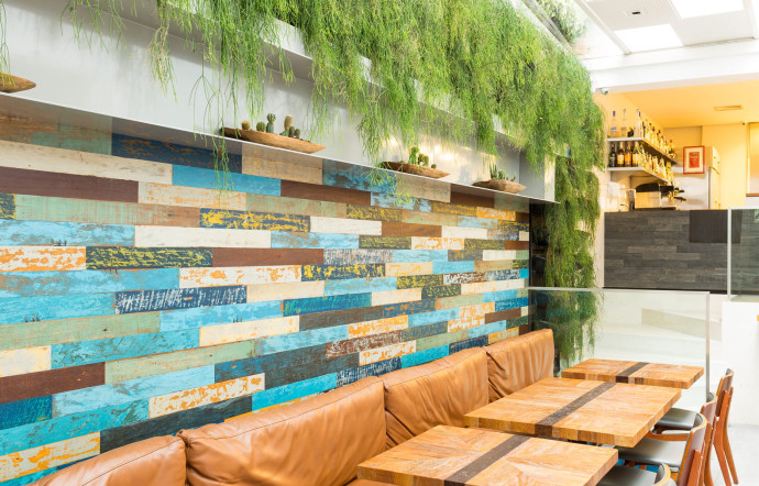 Un second espace, plus petit, se trouve sous une verrière avec un mur végétal et conduit vers la cuisine.