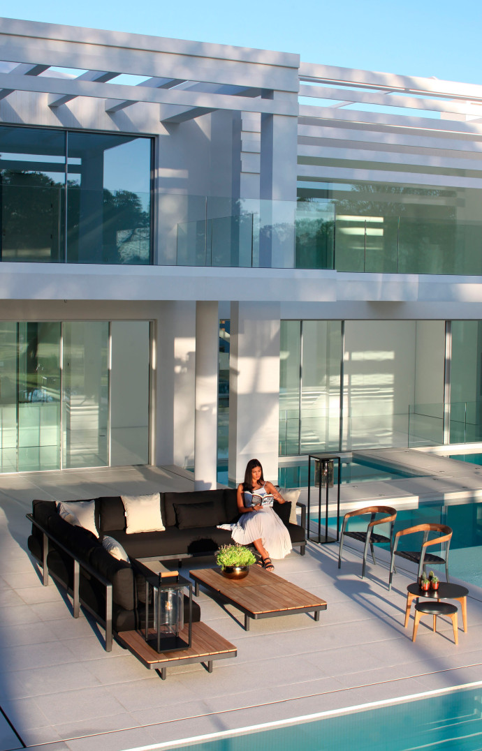 La marque belge Royal Botania. Canapé et tables basses « Alura Lounge », pieds en aluminium et revêtement en polyester, plateau en teck, et chaises « Jive », dos en teck, pieds en aluminium et assise en fibre d’oléfine.