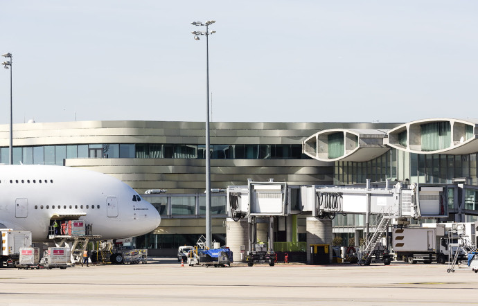 Opération de chargement de la soute sur fond de bâtiment de la liaison AC , terminal 2, Paris-Charle-de-Gaulle.