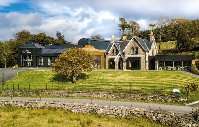 La distillerie depuis un champ avec un sorbier en été.