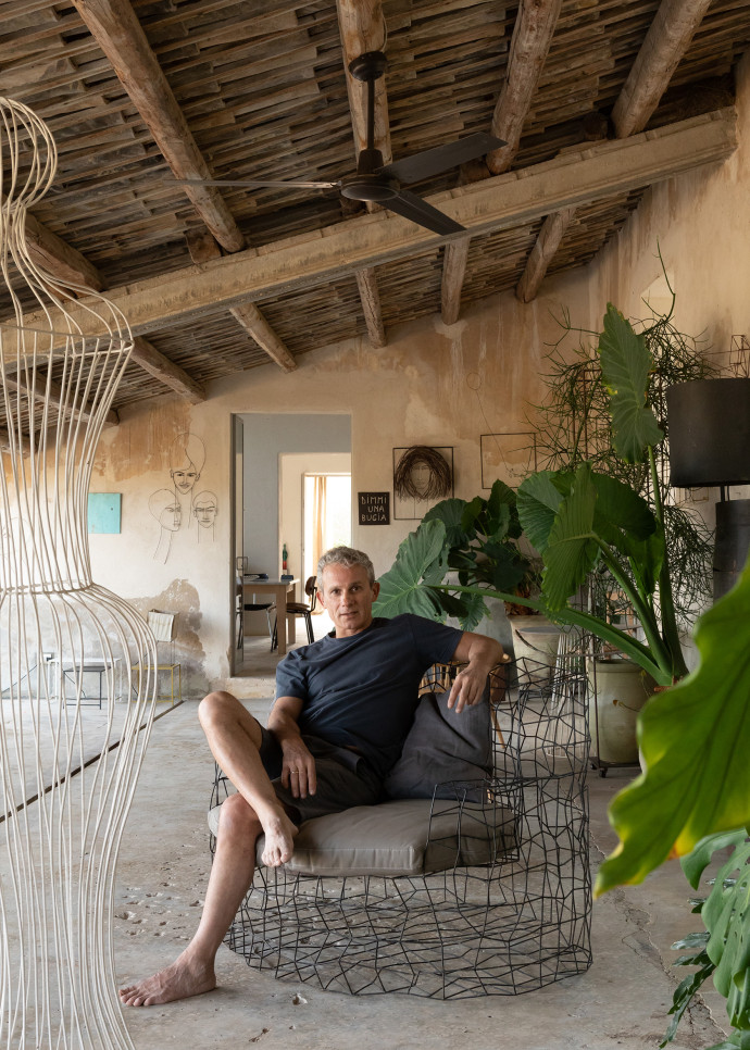 Le designer Antonino Sciortino, assis sous le portique de sa maison parmi plusieurs de ses œuvres en fil de fer, dont certaines sont des prototypes.